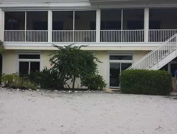 Raised coastal home with a screened upper porch and shutters on the ground floor