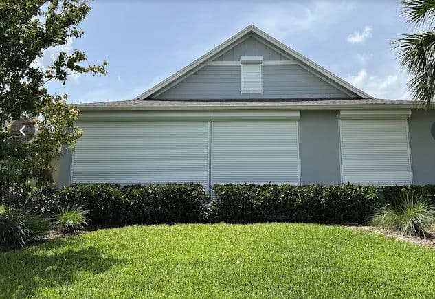Roll-down shutter closed across the lanai of a gray home