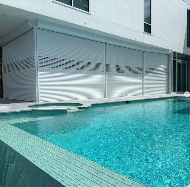 Roll-down shutters lowered on a two-story home beside a pool