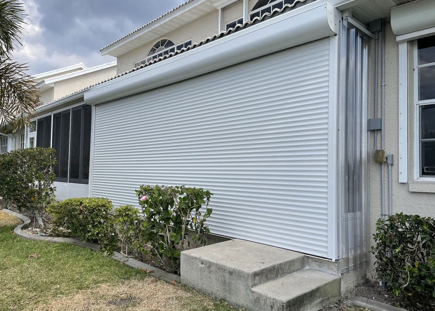 White home with roll-down shutters closed above front steps