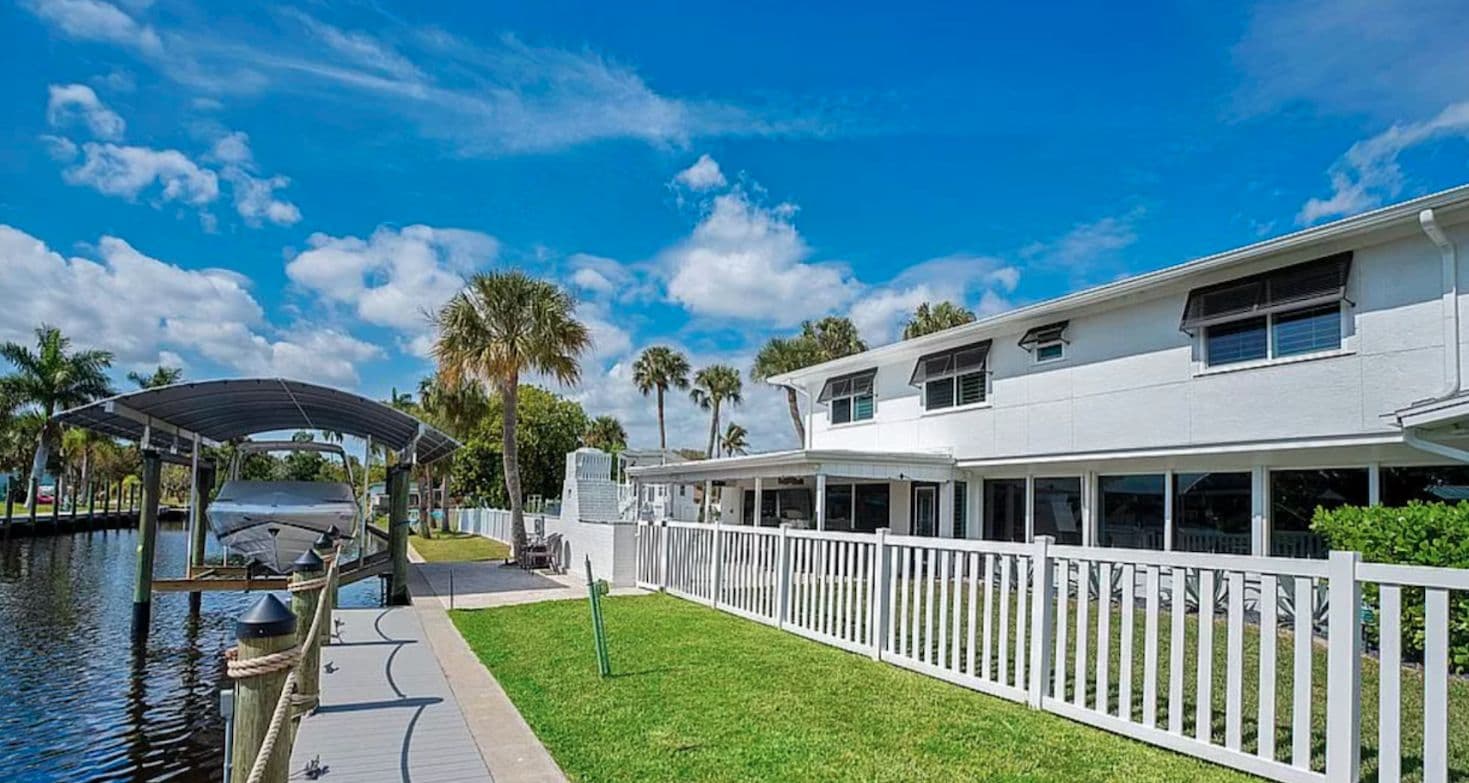 Canal-front home with a white fence and protected openings