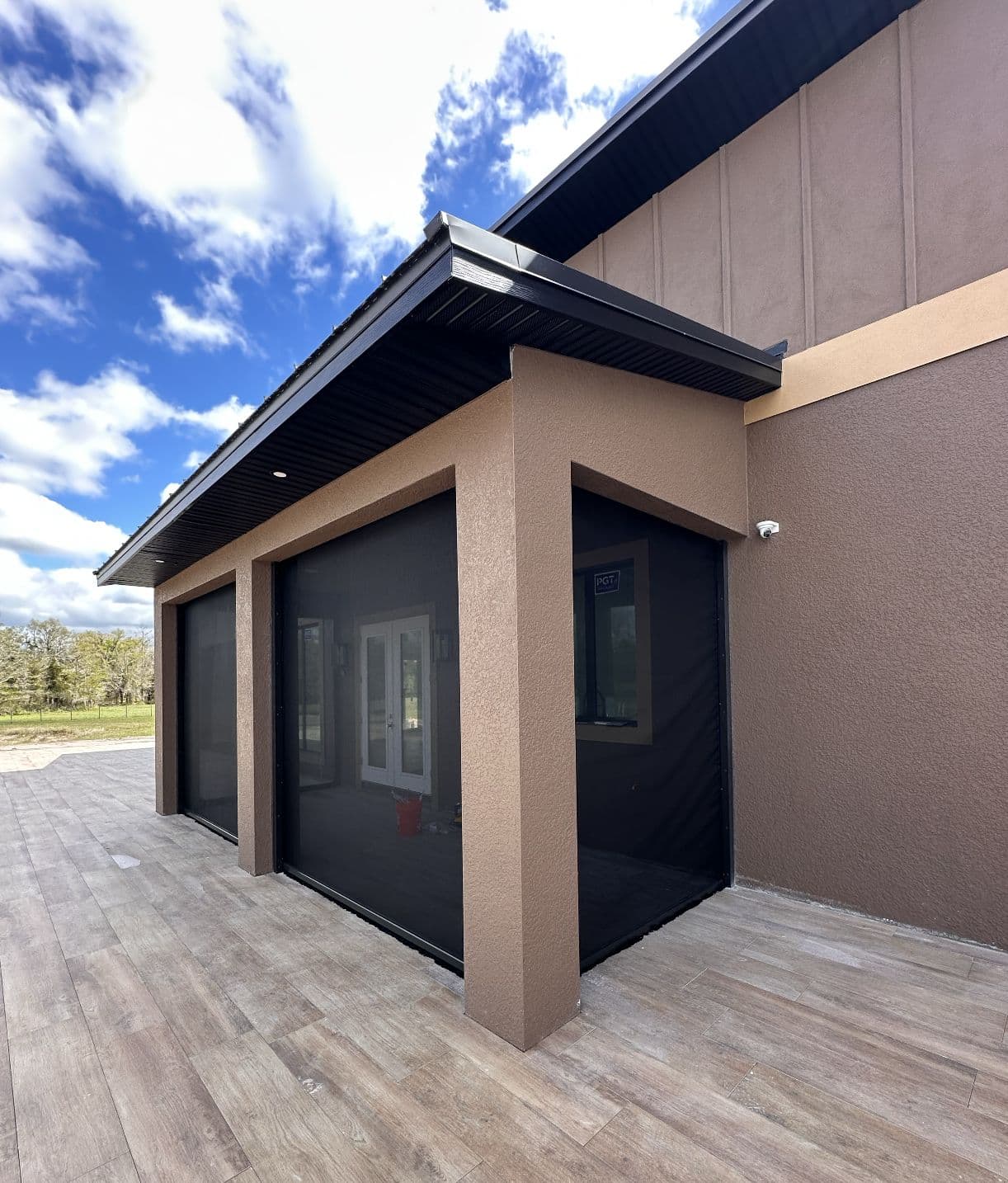 Modern stucco home with black screens lowered over its openings