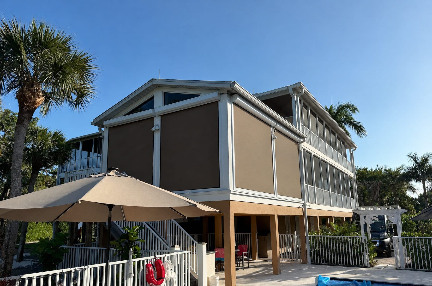 Raised home with tan screens lowered around the lanai