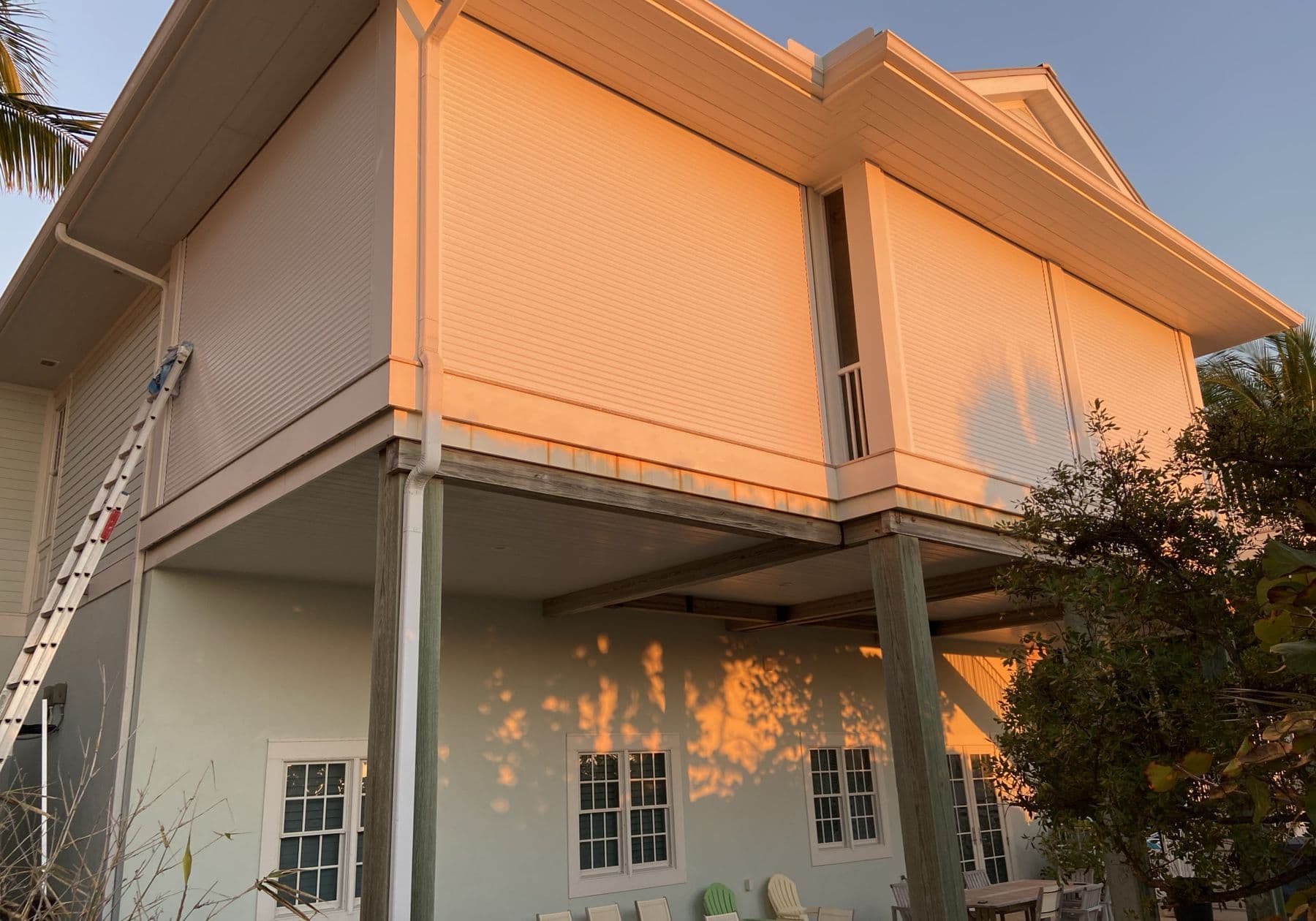 Raised stilt home at sunset with roll-down shutters closed on the upper floor