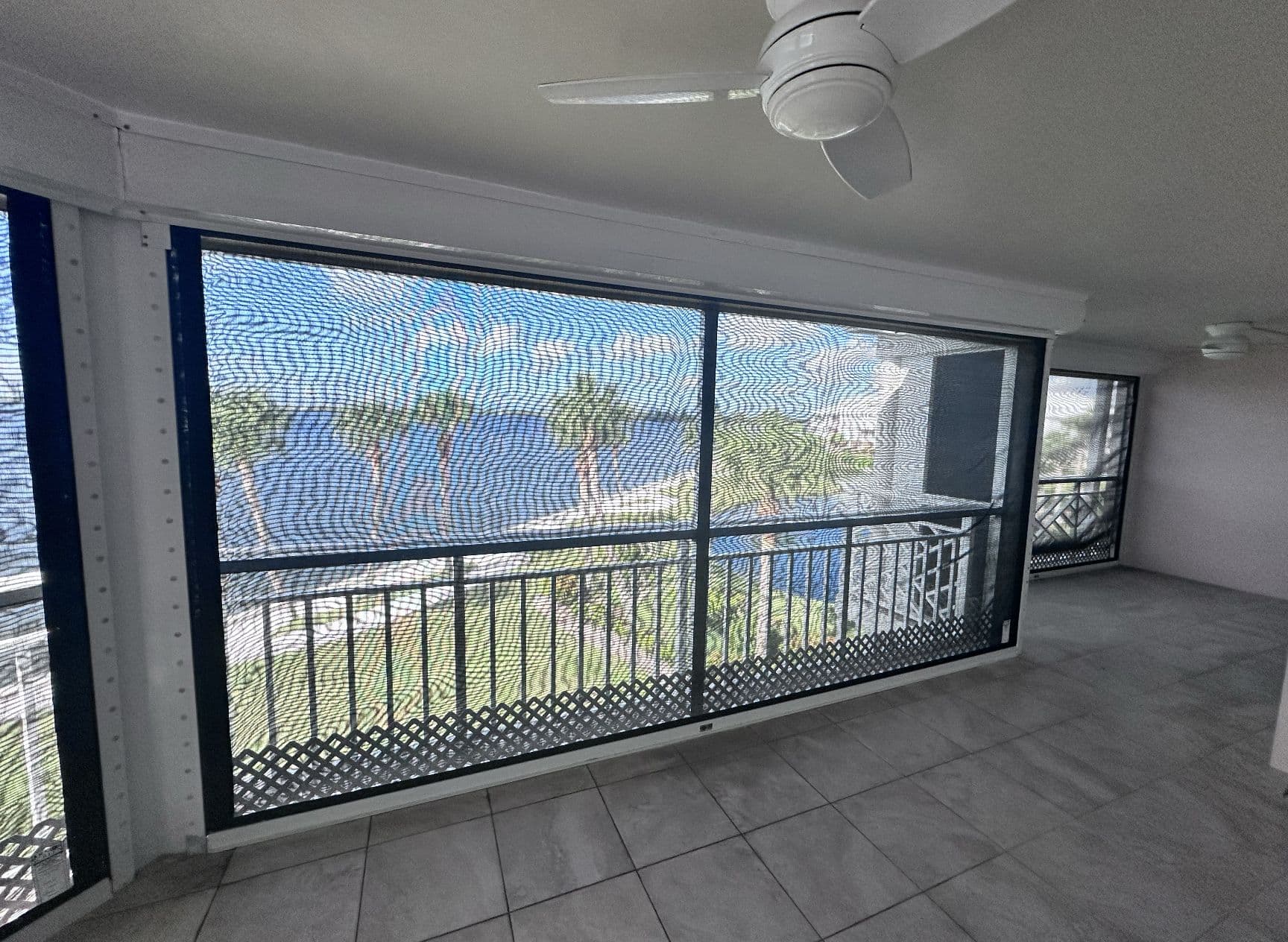 View of the water through a lowered screen on a covered lanai